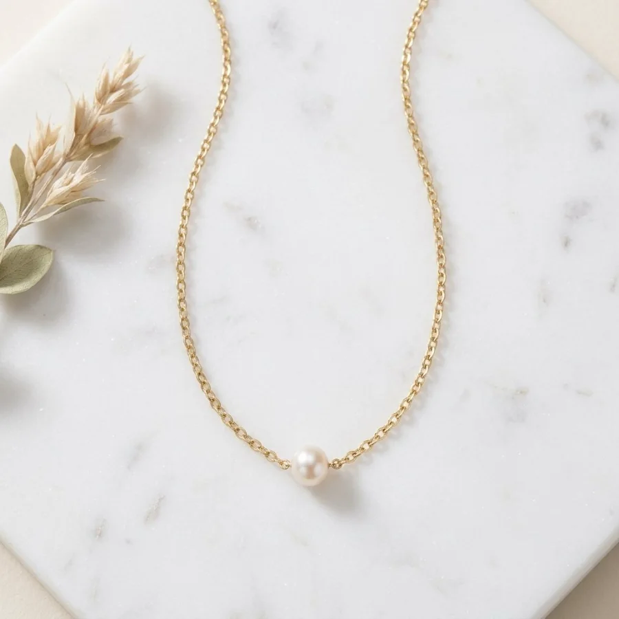 The necklace styled in a flat-lay scene on marble with dried flowers